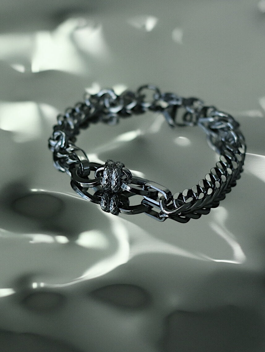 Monora Studio heavy stainless steel Cuban link bracelet with textured industrial knot reflecting on fluid water surface