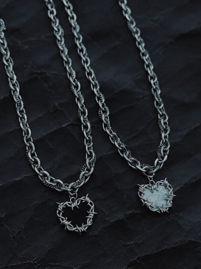 White and black enamel thorn heart necklaces, high-polish stainless steel liquid metal collection by Monora Studio.