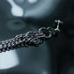 Macro cinematic shot of silver tassel chains on a reflective dark water-like surface, tarnish-proof hypoallergenic surgical steel jewelry.