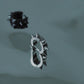 Polished silver and black stainless steel spiked huggie earrings on dark surface, durable alternative fashion accessories