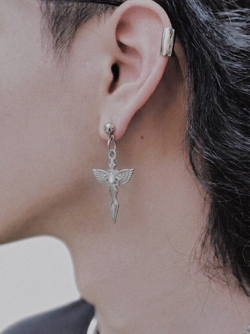 Close-up of model wearing Seraphim Blade winged earrings, long silver tassel wing drops, hypoallergenic stainless steel jewelry for alternative luxury.