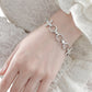 Model wearing Monora Studio stainless steel crescent moon flower link bracelet with white lace ruffle blouse close up⁠