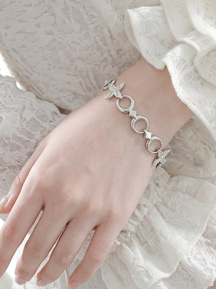 Model wearing Monora Studio stainless steel crescent moon flower link bracelet with white lace ruffle blouse close up⁠