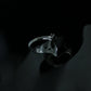 Tarnish-proof silver flowing flame ring on a dark reflective surface, high-shine industrial aesthetic jewelry, durable surgical steel.
