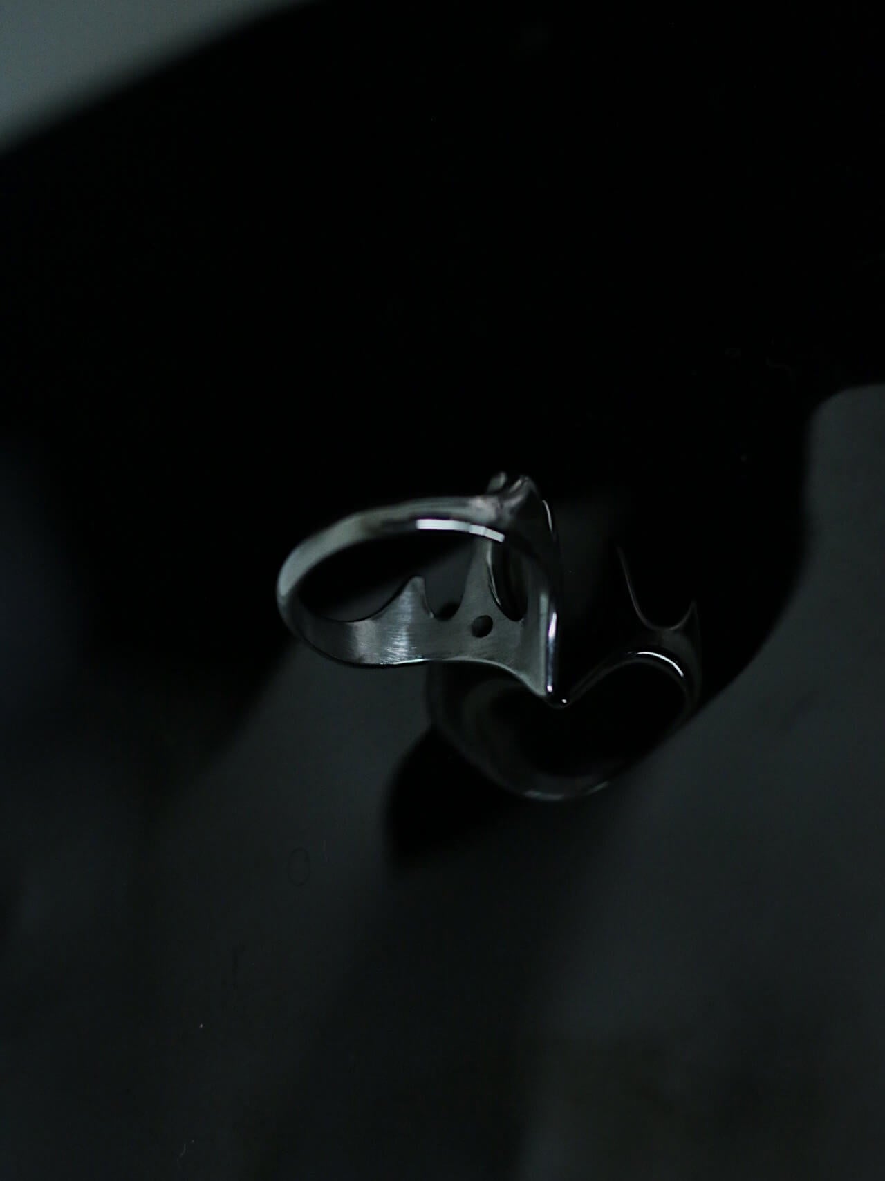 Tarnish-proof silver flowing flame ring on a dark reflective surface, high-shine industrial aesthetic jewelry, durable surgical steel.
