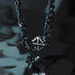 Monora Studio stainless steel heavy Cuban link chain with open work cross pendant reflecting on dark water surface⁠
