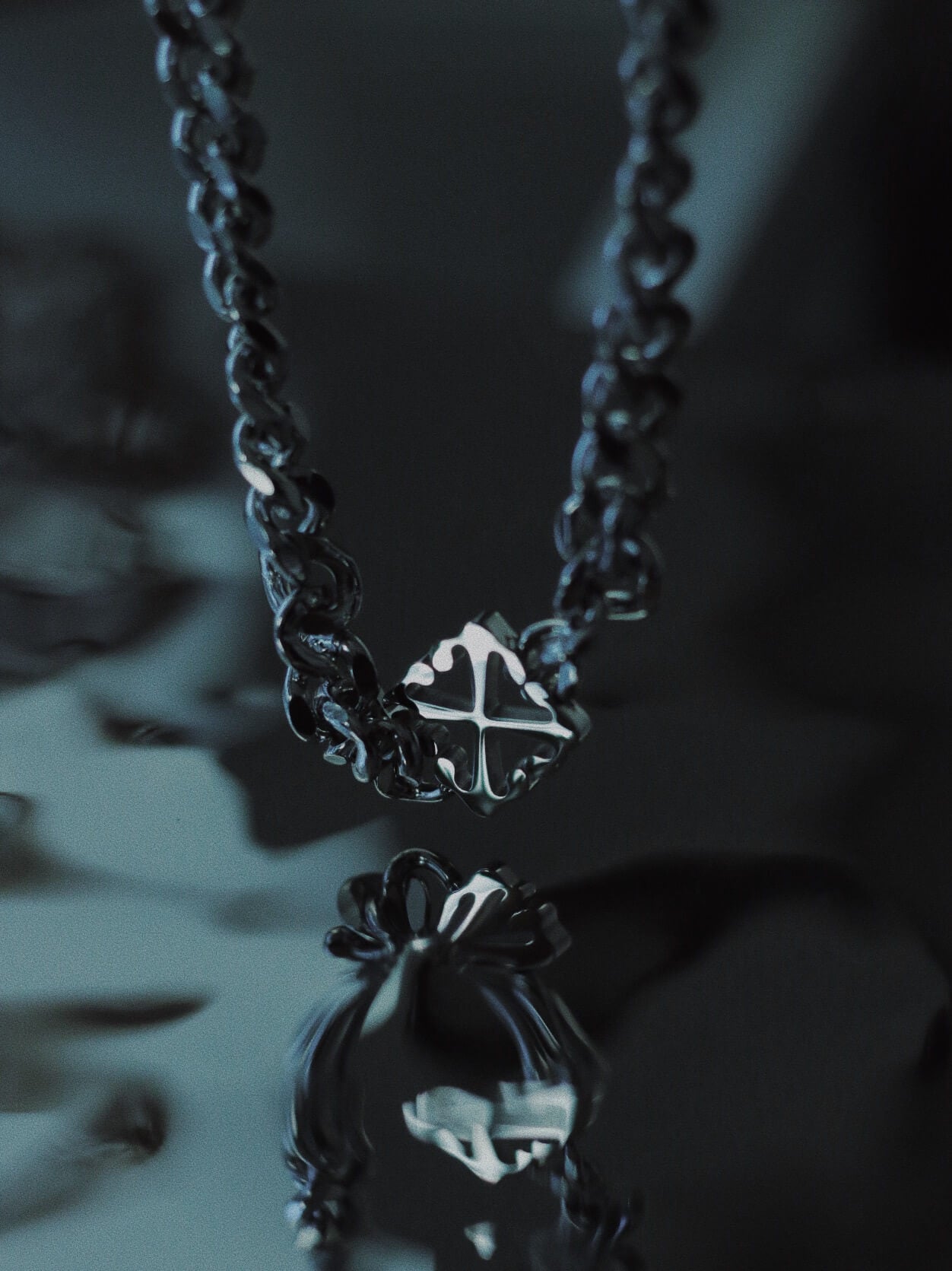 Monora Studio stainless steel heavy Cuban link chain with open work cross pendant reflecting on dark water surface⁠