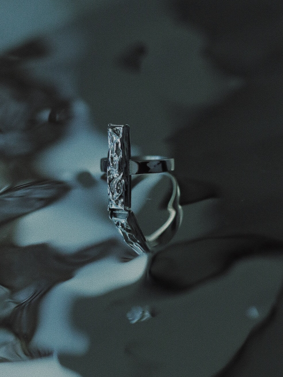 Monora Studio stainless steel vertical bar ring with molten texture reflecting on dark fluid water⁠