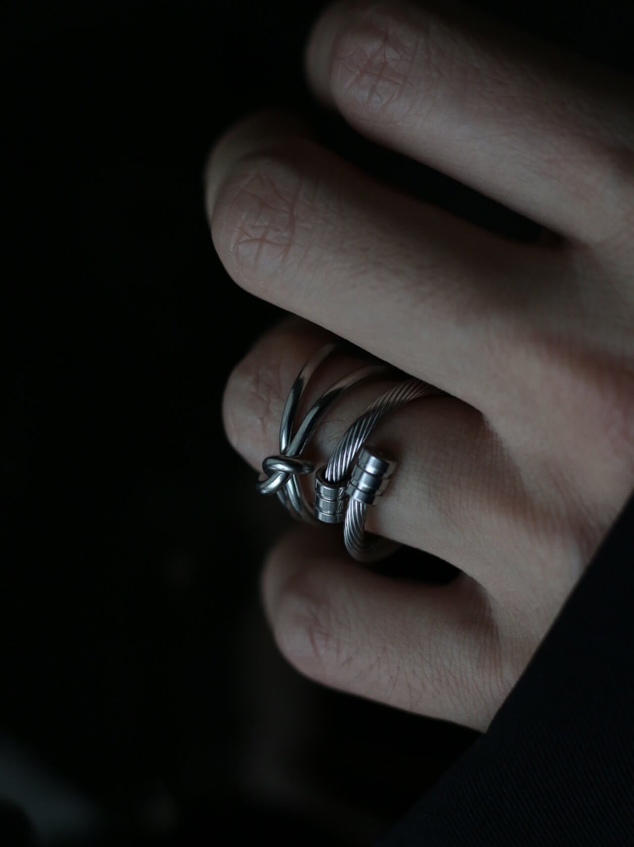 Moody lifestyle shot of a tarnish-proof stainless steel knot ring, aesthetic silver adjustable ring for stacking, durable fashion jewelry for daily wear.