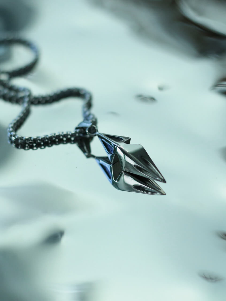 Monora Studio stainless steel spearhead pendant reflection on a metallic water surface close up shot⁠