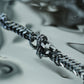 Macro close up shot of Monora Studio durable titanium steel entwined link curb chain bracelet on reflective background⁠