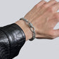 Man wearing Monora Studio silver color metallic knot Cuban chain bracelet paired with black leather jacket streetwear look⁠