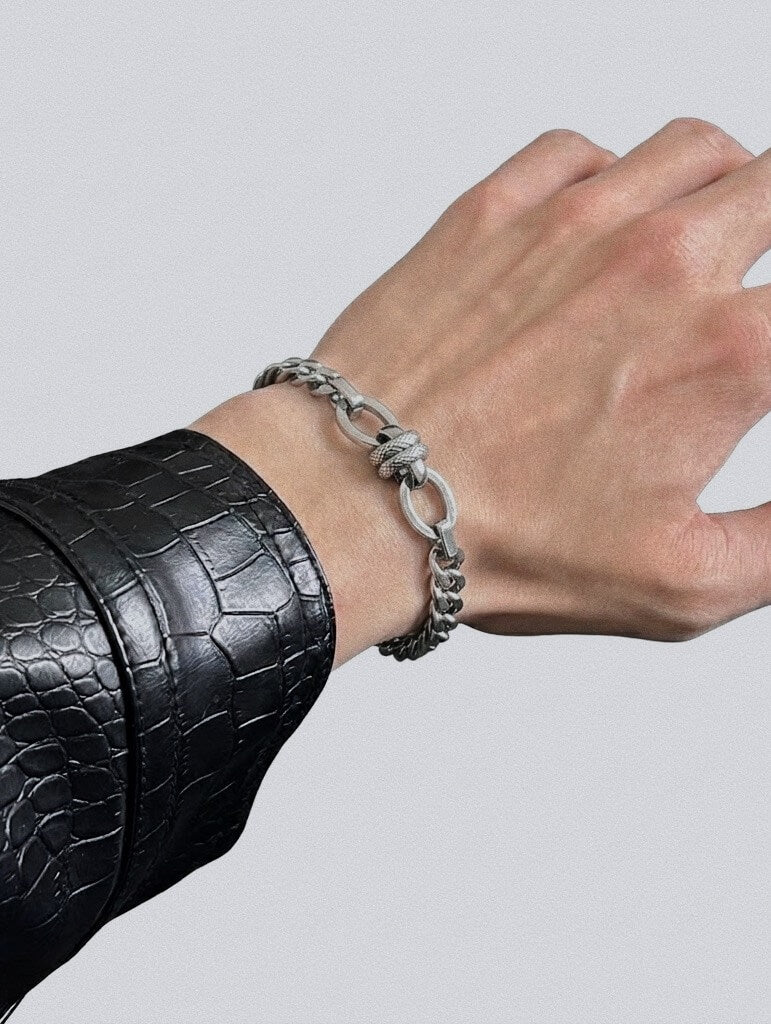 Man wearing Monora Studio silver color metallic knot Cuban chain bracelet paired with black leather jacket streetwear look⁠