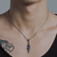 Male model wearing Monora Studio industrial titanium finish dagger necklace with a blue sapphire crystal inlay⁠