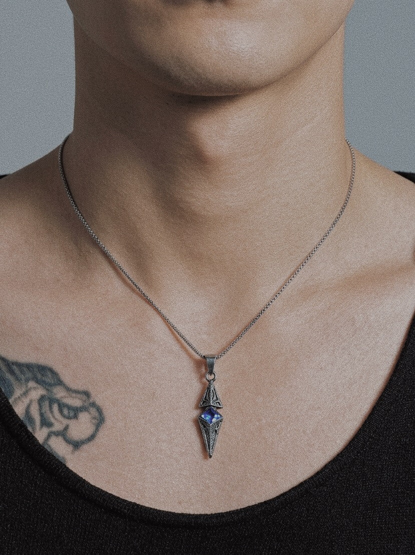 Male model wearing Monora Studio industrial titanium finish dagger necklace with a blue sapphire crystal inlay⁠