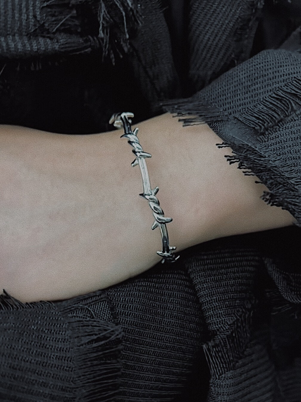 Model wearing Monora Studio punk style barbed wire open cuff bracelet with alt clothing streetwear outfit⁠