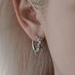 Close-up on-ear model wearing a thick stainless steel gothic hoop, alternative aesthetic street style earring, waterproof durable huggie jewelry.