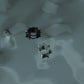 Polished silver and black stainless steel spiked huggie earrings on dark surface, durable alternative fashion accessories
