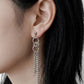 On-model profile shot of a silver chain tassel earring, asymmetrical subculture aesthetic jewelry, waterproof stainless steel drop earring for daily wear.