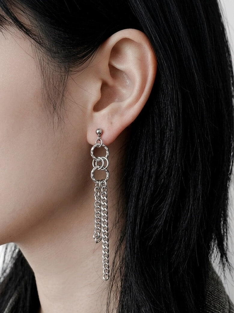 On-model profile shot of a silver chain tassel earring, asymmetrical subculture aesthetic jewelry, waterproof stainless steel drop earring for daily wear.