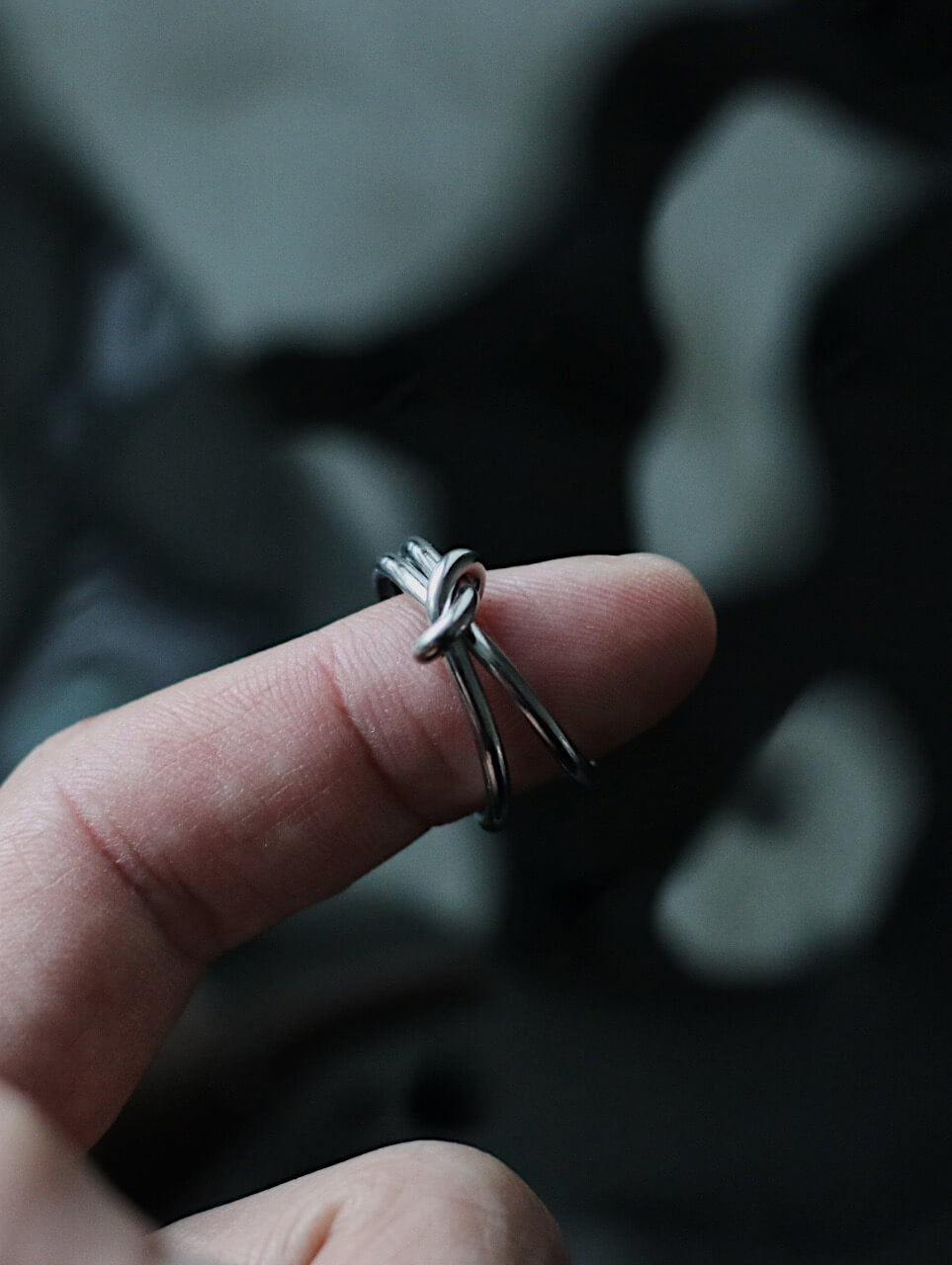 Close-up of a silver knot ring for women on finger, minimalist stainless steel double band adjustable jewelry, Monora Studio lifestyle.