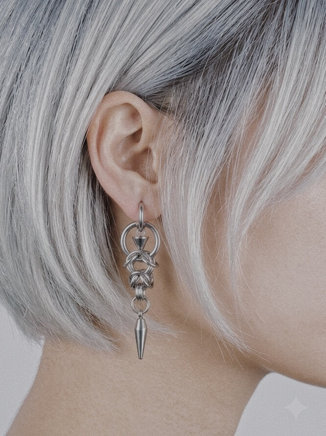 Model with silver hair wearing Monora Studio stainless steel industrial woven chain spike drop earring close up⁠